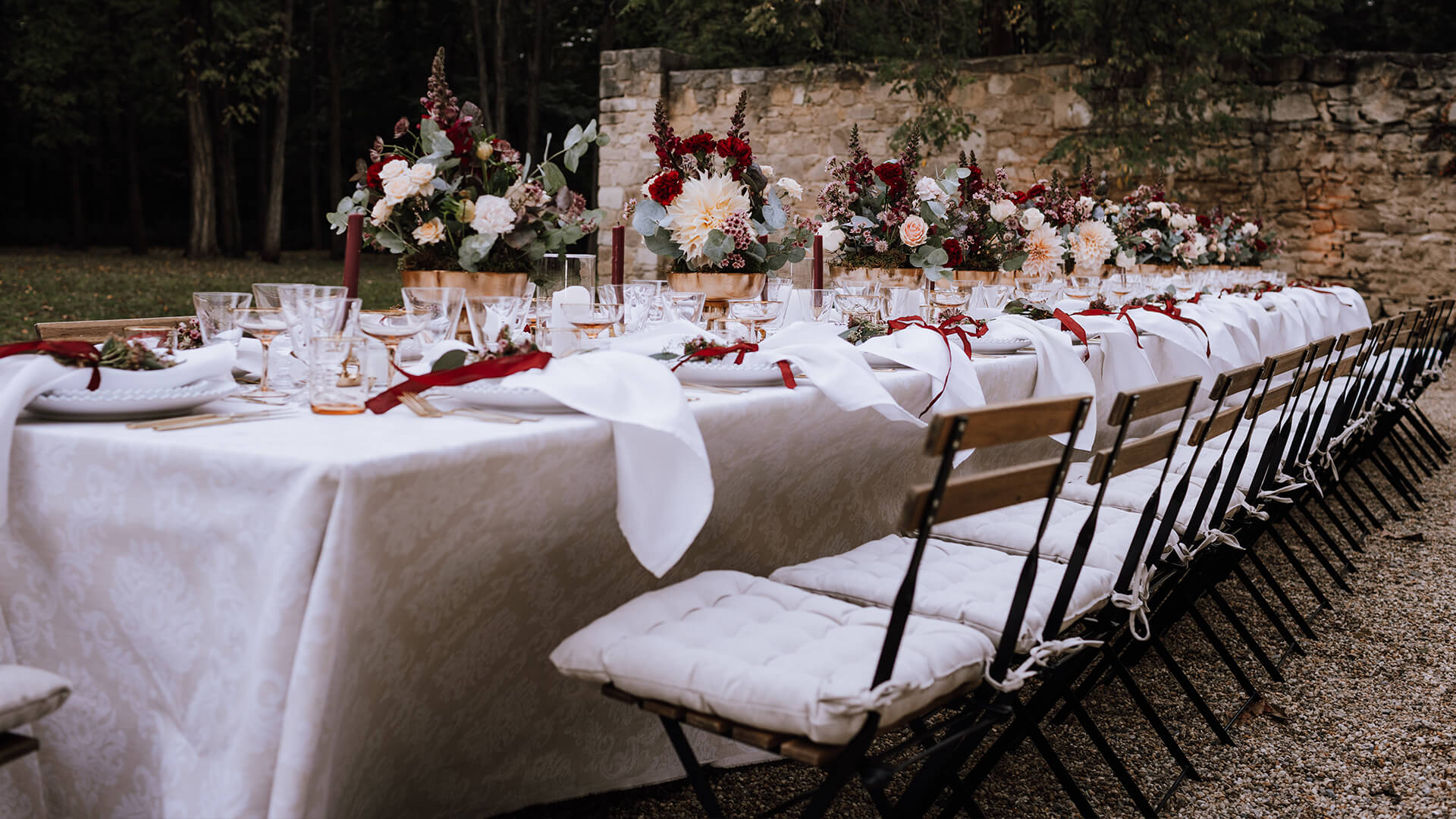 Gedeckter Hochzeitstisch im Freien mit weißen Tuch und Dekoration